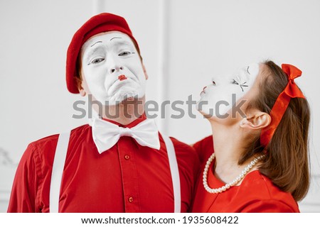 Two mime artists in red costumes, kissing scene