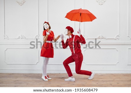 Mime artists in red costumes, scene with umbrella