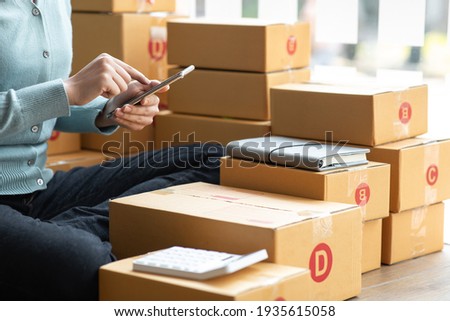 Starting small businesses SME owners female entrepreneurs Write the address on receipt box and check online orders to prepare to pack the boxes, sell to customers, sme business ideas online. Royalty-Free Stock Photo #1935615058