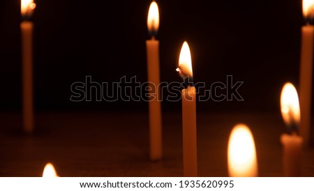 A candle that is shining with flames And there are other candles around