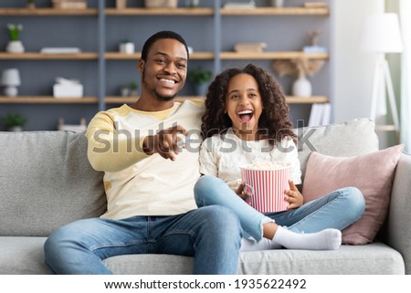 Happy black family father and daughter watching movie together
