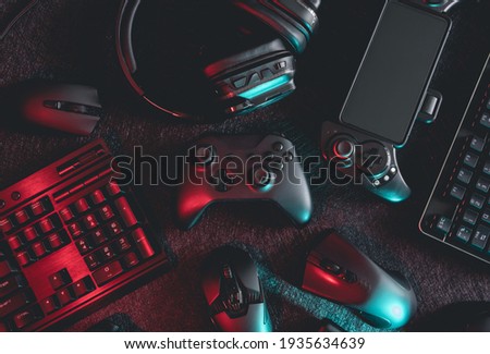 gamer work space concept, top view a gaming gear, mouse, keyboard, joystick, headset with rgb color on black table background. Royalty-Free Stock Photo #1935634639