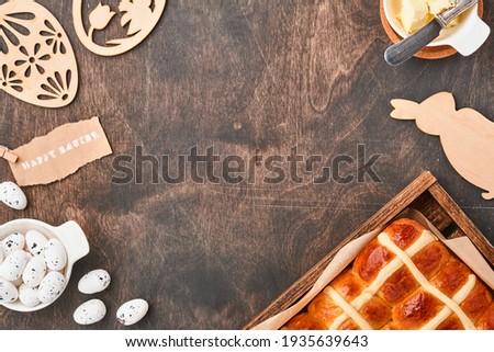 Easter Hot Cross Buns. Traditional breakfast and Easter baking holiday decorations rabbiton dark old wooden background. Bright colors, view from above on wooden table.