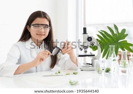 Child girl scientists learning science and looking germs and bacteria through magnifying glass in the laboratory. Education and science. Researcher and discovery concept. Early development of children