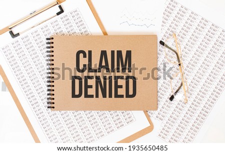 Craft colour notepad with text CLAIM DENIED . Notepad with eyeglasses and text documents. Business concept