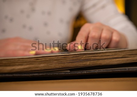 Woman looks through an family album with old photos at table at home.