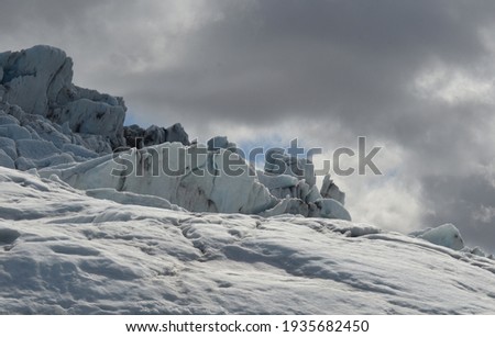 Dark gray storm clouds over a snow covered glacier.