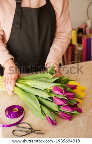 Young woman florist makes a bouquet of tulips in floral shop