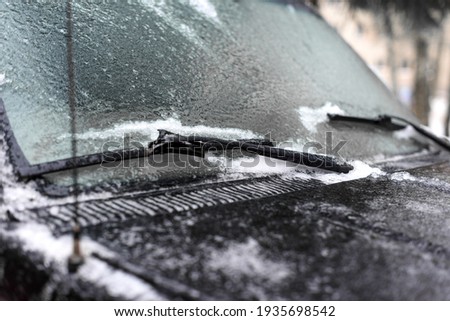 the windshield of the car is icy. frozen wipers.winter driver problem.