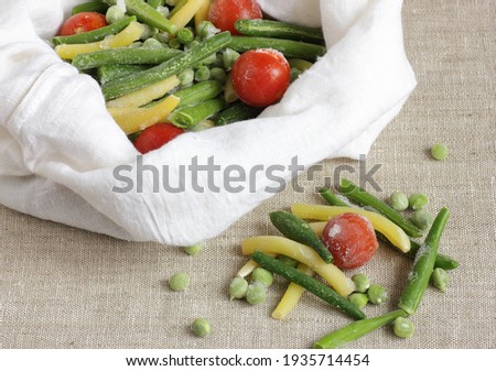 Frozen vegetables in plastic free zero waste cloth bag on linen fabric background, closeup, saving leftovers, food storage and eco friendly, reusable, sustainable bag concept