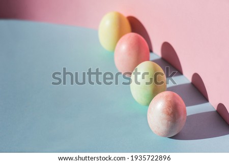 Trend pastel colorful Easter eggs on pink and blue background. An Easter card with a copy of the place for the text.