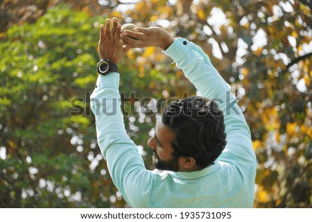 Indian man in action of catching ball in cricket match