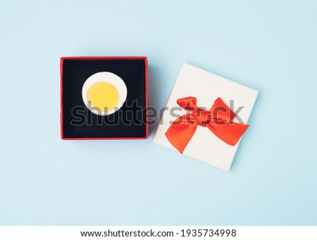 Egg in a ring box. Creative funny story for Easter on a light blue background