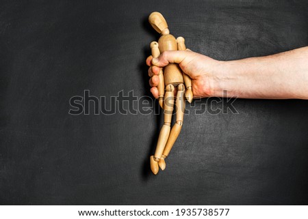 wooden man is grabbed by a man hand. The concept of helplessness and submission Royalty-Free Stock Photo #1935738577