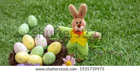 Easter eggs hunt concept. Happy Easter greeting card. Christian religion holiday celebration and decoration. Pastel colors eggs in a nest on green grass, outdoors in nature, closeup view.