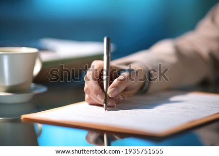 Close up of an entrepreneur hand filling out form in the night at office