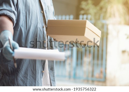 The businessman was wearing denim jacket with blue protective gloves and filed paperwork to sign package of orders ordered with the customer to the front of the house. Fast service shipping concept
