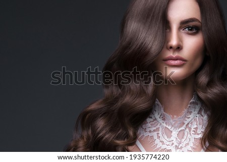Beautiful brown-haired girl with a perfectly curls hair, and classic make-up. Beauty face and hair. Royalty-Free Stock Photo #1935774220