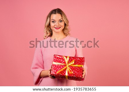 Winter holiday, a young woman in a pink sweater on a pink background