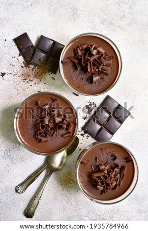 Homemade delicious chocolate mousse or panna cotta  in a glasses on a light slate, stone or concrete background. Top view with copy space. Royalty-Free Stock Photo #1935784966