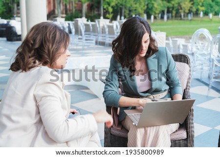 Wedding planners, organizers, event decorators, managers with laptop.Business meeting,negotiations,project discussion,signing contract with client,customer.Women, girls in stylish suits in restaurant. Royalty-Free Stock Photo #1935800989