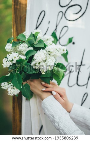 girl holds a bouquet of white lilac in her hands on a white background