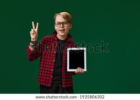 child boy in red checkered shirt shows empty tablet