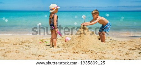 Sibling boy building a sandcastle at the beach in summer Royalty-Free Stock Photo #1935809125