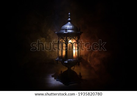 Arabic lantern with candle at night for Islamic holiday. Muslim holy month Ramadan. The end of Eid and Happy New Year. Copy space on dark background. Royalty-Free Stock Photo #1935820780