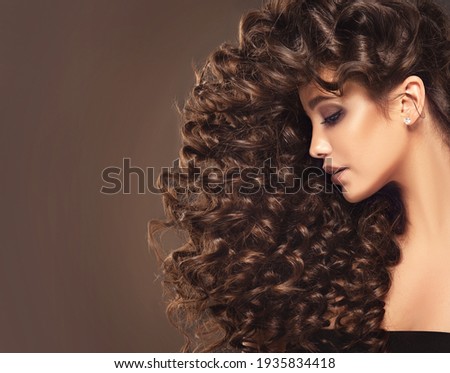 Brunette  girl with long  and   shiny curly  hair .  Beautiful  model woman  with wavy hairstyle  Royalty-Free Stock Photo #1935834418