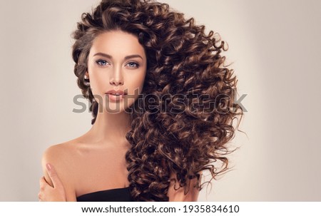 Brunette  girl with long  and   shiny curly  hair .  Beautiful  model woman  with wavy hairstyle  Royalty-Free Stock Photo #1935834610