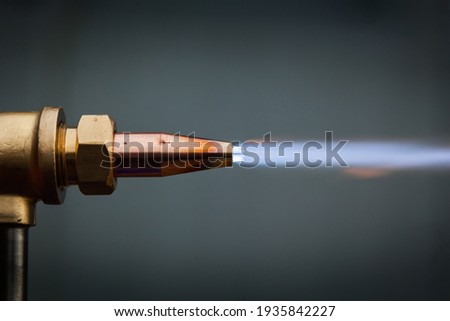 Gas cutter with copper nozzle with a stream of fire.  Royalty-Free Stock Photo #1935842227