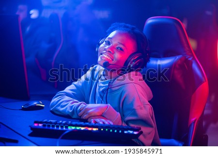 Professional Streamer African young woman cyber gamer in neon color blur background.