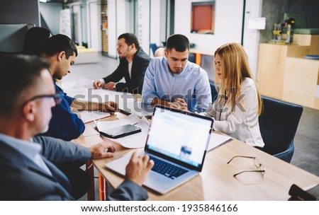 Male employer connecting to office internet for checking banking account during office brainstorming with colleagues, businessman using netbook application for browsing financial report on website