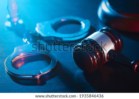 Handcuffs and wooden gavel. Crime and violence concept. Royalty-Free Stock Photo #1935846436