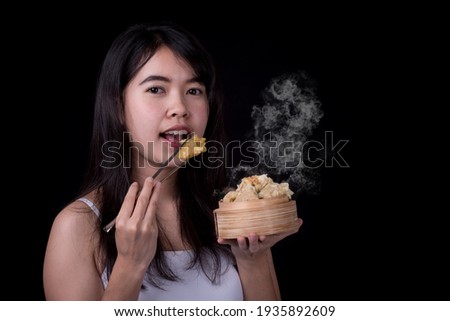 Portrait of beautiful girls holding dumpling isolated on black background. young Asian model.