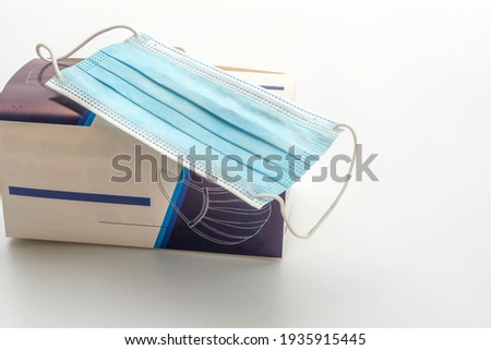 Medical three-layer mask on a paper box, isolated on white background.