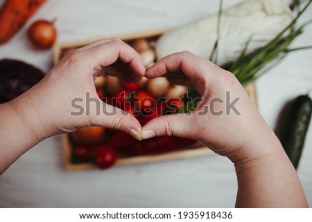 Hands making heart sign on vegetable background