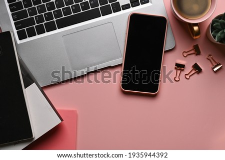 Flat lay office desk. Female workplace with smart phone, computer laptop and accessories on pink pastel background.