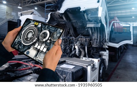 Serviceman repairing a truck using augmented reality application. Royalty-Free Stock Photo #1935960505
