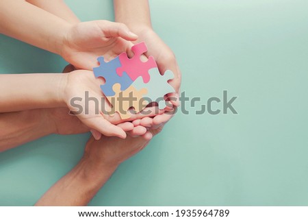 Adult and chiildren hands holding jigsaw puzzle shape, Autism awareness,Autism spectrum disorder family support concept, World Autism Awareness Day
