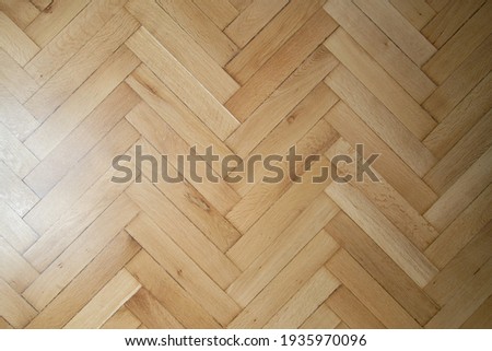 Classic old wooden parquet laying in the form of a herringbone in light brown color.