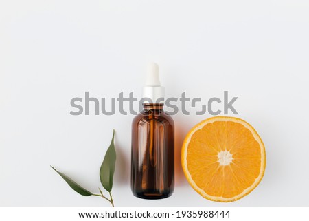 Orange essential oil in glass bottle with green leaf. Cosmetic concept on white background, isolated flat lay. High quality photo