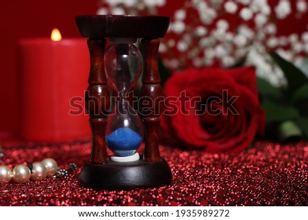 Candle With Hourglass, Rose and Jewelry Box on Red Velvet Background