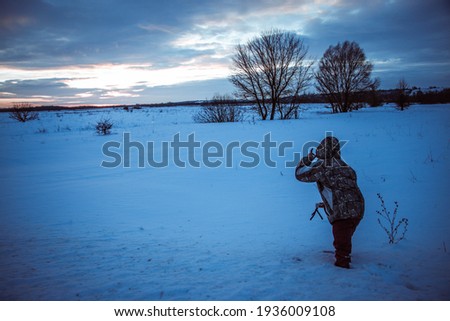 Man with phone on tripod making time-lapse photographs of winter zidio sunset.