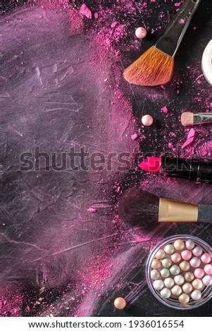 Make-up brushes, pearls, lipstick, top shot on a dark background