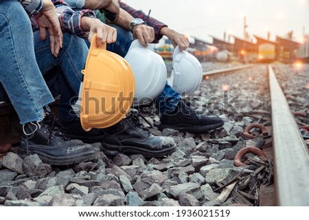 A group of workers holding hard hat and engineers rested on the tracks after their hard work. Teamwork engineer work together in a construction railway. 