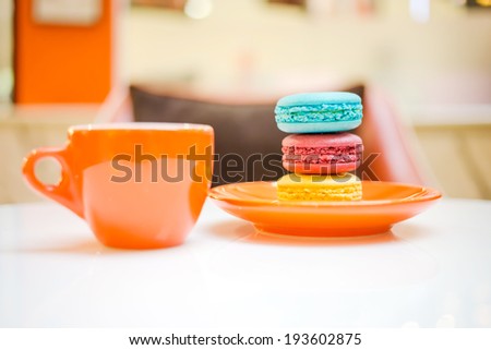 Colorful macarons with orange coffee cup