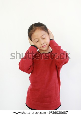 Portrait of happy Asian little child placing hands on ears. Joyful kid closed eyes and smiling on white isolated background