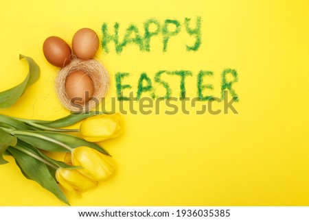 inscription happy easter from grass with bunny eggs, flowers tulips and nest on a yellow background. copy space for text